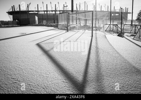 Gefrorener Fußballplatz mit Schnee und Stadion im Hintergrund Stockfoto