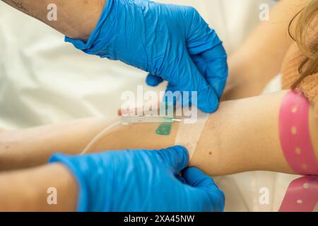 Arzt, der einen IV-Katheter in den Arm eines Patienten einführt. Stockfoto