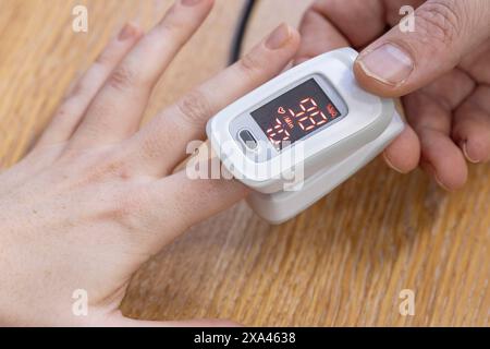 Fingertipp-Pulsoximeter am Finger einer Person. Stockfoto