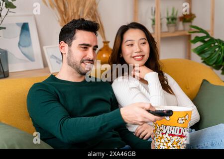 Ein Paar genießt einen Film auf der Couch mit Popcorn Stockfoto
