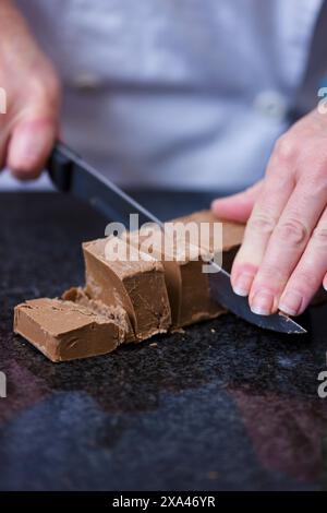 Nahaufnahme eines Chefs Hände schneiden Schokolade block Stockfoto