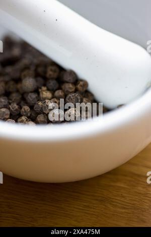 Mörser und Stößel gefüllt mit schwarze Pfefferkörner Stockfoto