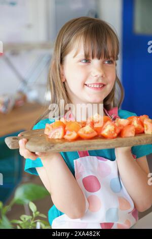 Lächelnde junge Mädchen halten hacken Board mit Tomaten Stockfoto