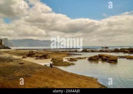 Eine ruhige Küstenlandschaft mit einer sanften Flut, die sich um Felsvorsprünge unter einem Himmel mit verstreuten Wolken schwebt. Stockfoto