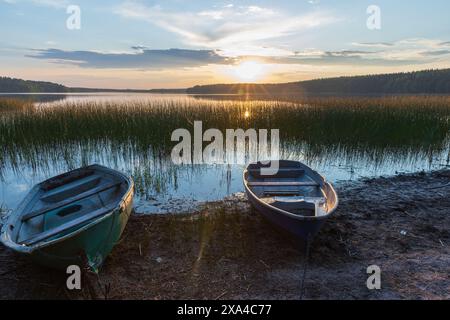 Kleine Ruderboote liegen an der Seeküste unter Sonnenuntergang Himmel, karelisches Landschaftsfoto Stockfoto