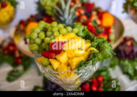 Großes Tablett mit frischen Früchten, einschließlich Ananas, grüne Trauben, Erdbeeren und andere Beeren Stockfoto