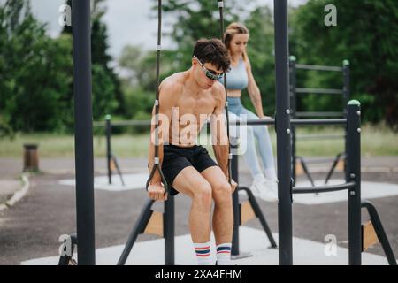 Outdoor-Calisthenics-Workout mit zwei Athleten, die an parallelen Bars und Ringen trainieren Stockfoto