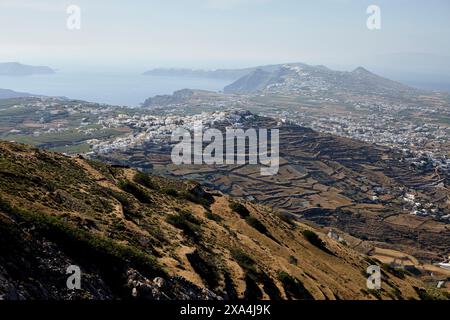 Ein atemberaubender Blick auf eine Küstenstadt mit weißen Gebäuden, eingebettet zwischen Terrassenhügeln, mit Blick auf das Meer mit Bergen in der Ferne. Stockfoto