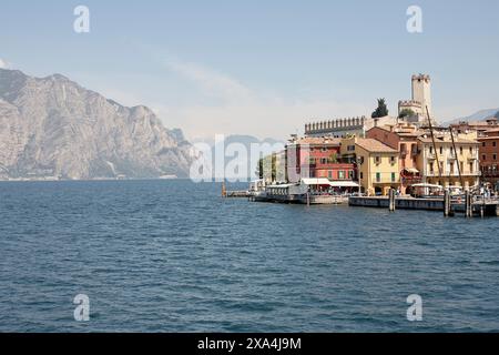 Ein ruhiger Blick auf eine malerische Stadt am See mit farbenfrohen Gebäuden vor dem Hintergrund der majestätischen Berge und eines klaren blauen Himmels. Stockfoto