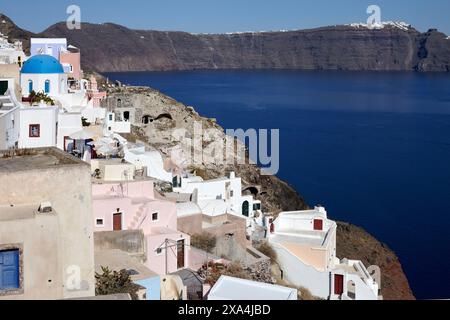 Ein malerischer Blick auf Oia, Santorini, mit seinen berühmten weißen Gebäuden, blauen Kuppeln und der ruhigen Ägäis im Hintergrund. Stockfoto