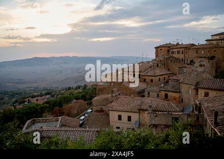 Blick auf den Sonnenuntergang über eine alte Stadt auf einem Hügel mit Terrakottadächern, umgeben von einer ländlichen Landschaft. Stockfoto