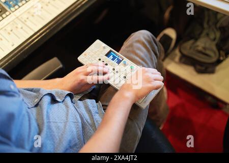 Eine Person bedient einen Audiomischer und konzentriert sich dabei auf die Anpassung der Einstellungen mit den Händen. Stockfoto