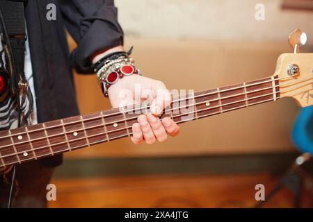 Eine Nahaufnahme der linken Hand einer Person, die das Griffbrett einer Gitarre spielt, wobei die Finger auf die Saiten drücken. Stockfoto