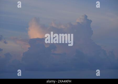 Ein heiterer Himmel mit weichen Wolken, die von der untergehenden oder aufgehenden Sonne in rosa Tönen getönt sind. Stockfoto