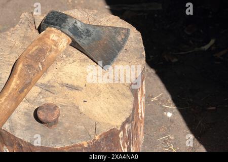 Die Axt liegt auf einem Holzdeck. Als Nächstes ist ein Hammerbock zum Nieten einer Sense. Stockfoto