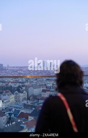 Frau, die die Skyline der Stadt während der Dämmerung ansieht. Stockfoto