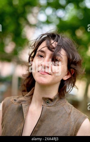 Selbstbewusste junge Frau mit einem fröhlichen Ausdruck, die draußen steht. Stockfoto