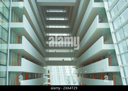 Moderne architektonische Innenausstattung eines Gebäudes mit symmetrischen Böden, Glasfassade und Tageslicht. Stockfoto
