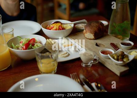 Ein frisches kontinentales Frühstück mit einer Auswahl an Speisen wie Brot, Salat, Obst und Getränken auf einem Holztisch. Stockfoto