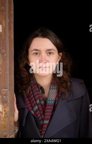Eine Frau, die in einem Türdurchgang steht und einen Schal und einen Mantel trägt. Stockfoto