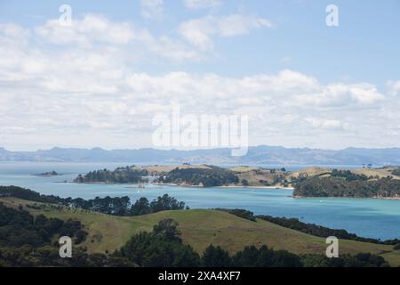 Malerische Aussicht auf eine üppige Küstenlandschaft mit klarem blauem Wasser unter einem teilweise bewölkten Himmel. Stockfoto