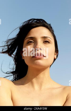 Sonnenlicht-Porträt einer Frau, die in die Ferne vor einem klaren Himmel blickt. Stockfoto