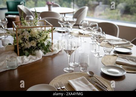 Eleganter Esstisch für besondere Veranstaltungen, mit einem schönen Blumenaufsatz, Weingläsern und fein angeordneten Utensilien Stockfoto