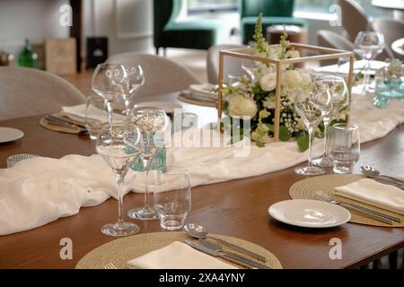 Eleganter Esstisch für besondere Veranstaltungen, mit einem schönen Blumenaufsatz, Weingläsern und fein angeordneten Utensilien Stockfoto