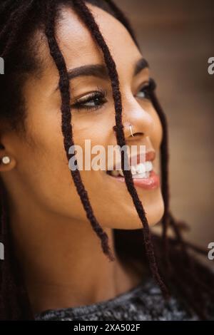 Porträt einer jungen, schönen Frau mit Dreadlocks, die ihr Gesicht bedecken. Stockfoto