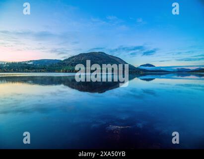 Ruhiger See mit spiegelähnlicher Reflexion unter einem Abendhimmel mit verstreuten Wolken. Loch Lochy Stockfoto