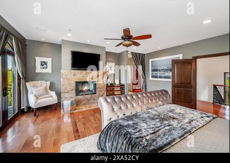 Elegant eingerichtetes Schlafzimmer mit geräumigen Fenstern und Holzfußboden Stockfoto
