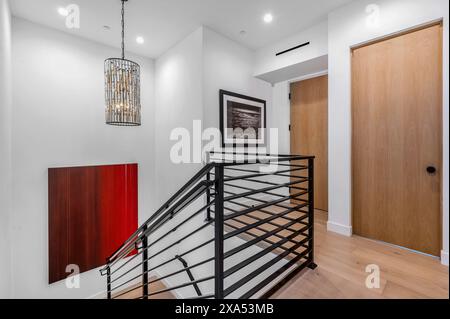 Moderne Holztreppe mit elegantem schwarzem Geländer und weißen Wänden in stilvollem Eingangsbereich Stockfoto