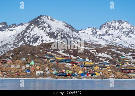 Südöstliches Grönland, Region Ammassalik. Typische farbenfrohe Häuser in der abgelegenen Gemeinde Tasiilaq. Malerische Aussicht auf das schnelle Eis im Frühling. Nur redaktionell. Stockfoto