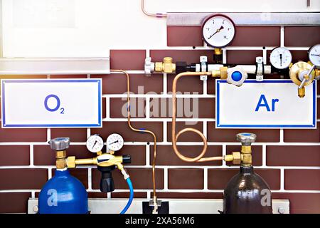 Sauerstoff- und Argonzylinder und Rohrleitungen mit Manometern Stockfoto