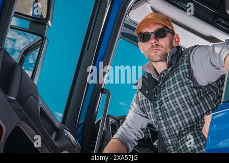 Ein Mann mit Sonnenbrille sitzt auf dem Fahrersitz des LKW Stockfoto