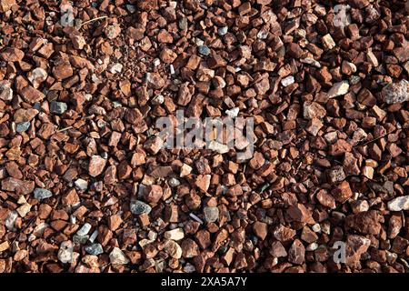 Ein Blick von oben auf braune Felsen und Kies an einem sonnigen Strand Stockfoto