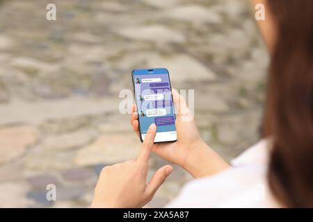 Frau, die draußen per Handy schreibt, Nahaufnahme. Gerätebildschirm mit Meldungen Stockfoto