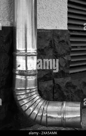 Teil der Wand mit verzinktem Rohr zum Ablassen von Regenwasser. Seitenansicht. Schwarzweißfoto. Nahaufnahme. Selektiver Fokus. Kopierbereich. Stockfoto