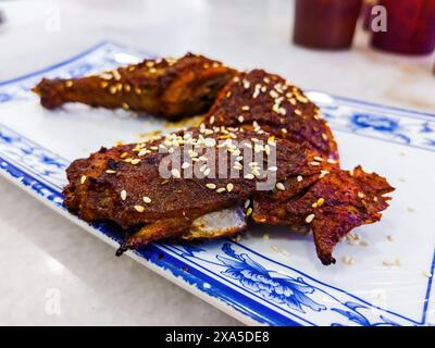 Gegrilltes Hühnchen mit scharfer Sauce, serviert in chinesischer Art mit Sesamsamen. Stockfoto