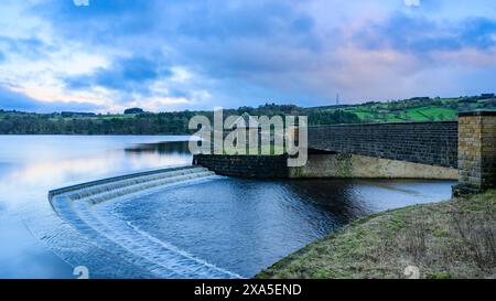 Wasser stürzt Stufen vom ruhigen malerischen künstlichen See herunter, unter einer Steinbrücke (blauer Abendhimmel und dunkle Wolken) - Swinsty Reservoir, England Großbritannien. Stockfoto