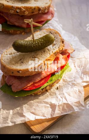 Zwei Schinkensandwiches mit Gurken und Tomaten auf Sandwichpapier Stockfoto