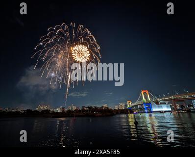 Ein malerischer nächtlicher Blick auf das Feuerwerk in der Bucht von Tokio und die Regenbogenbrücke in Odaiba, Tokio, Japan Stockfoto