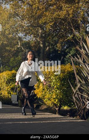 Eine Geschäftsfrau läuft einen Weg in einem Park. Sie trägt ein weißes Hemd und eine schwarze kurze Hose mit Strumpfhosen, sie läuft in einer hu Stockfoto