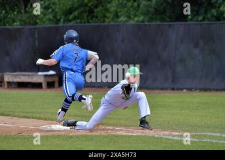 Illinois, USA. Frist Baseman reicht bis zum Fänger, während der Baserunner sicher an der ersten Basis ankommt. Stockfoto