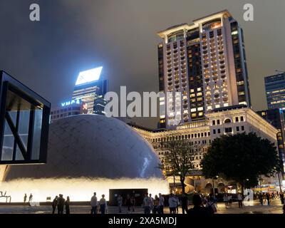 Nächtlicher Blick auf das Hong Kong Space Museum mit dem großen Peninsula Hotel im Hintergrund Stockfoto