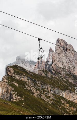 Ein Berglift-Sessel hängt an Drähten über einem üppigen Tal Stockfoto