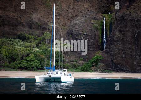 Ein kleines Boot vor einem kaskadierenden Wasserfall in Kauai Stockfoto