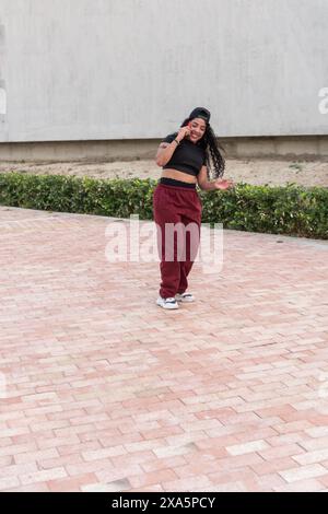 Junge Frau in Freizeitkleidung, die draußen läuft und telefoniert. Stockfoto