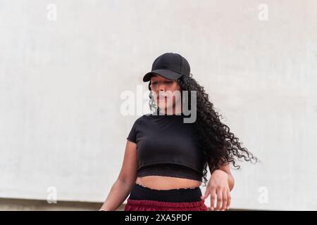 Junge Frau in sportlicher Freizeitkleidung mit lockigem Haar im Freien. Stockfoto