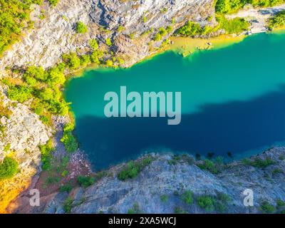 Wunderschöner Blick aus der Vogelperspektive auf den verlassenen Kalksteinbruch Velka Amerika in Tschechien mit türkisfarbenem Wasser und umliegendem Grün in hellem Sommersonnenlicht. Stockfoto